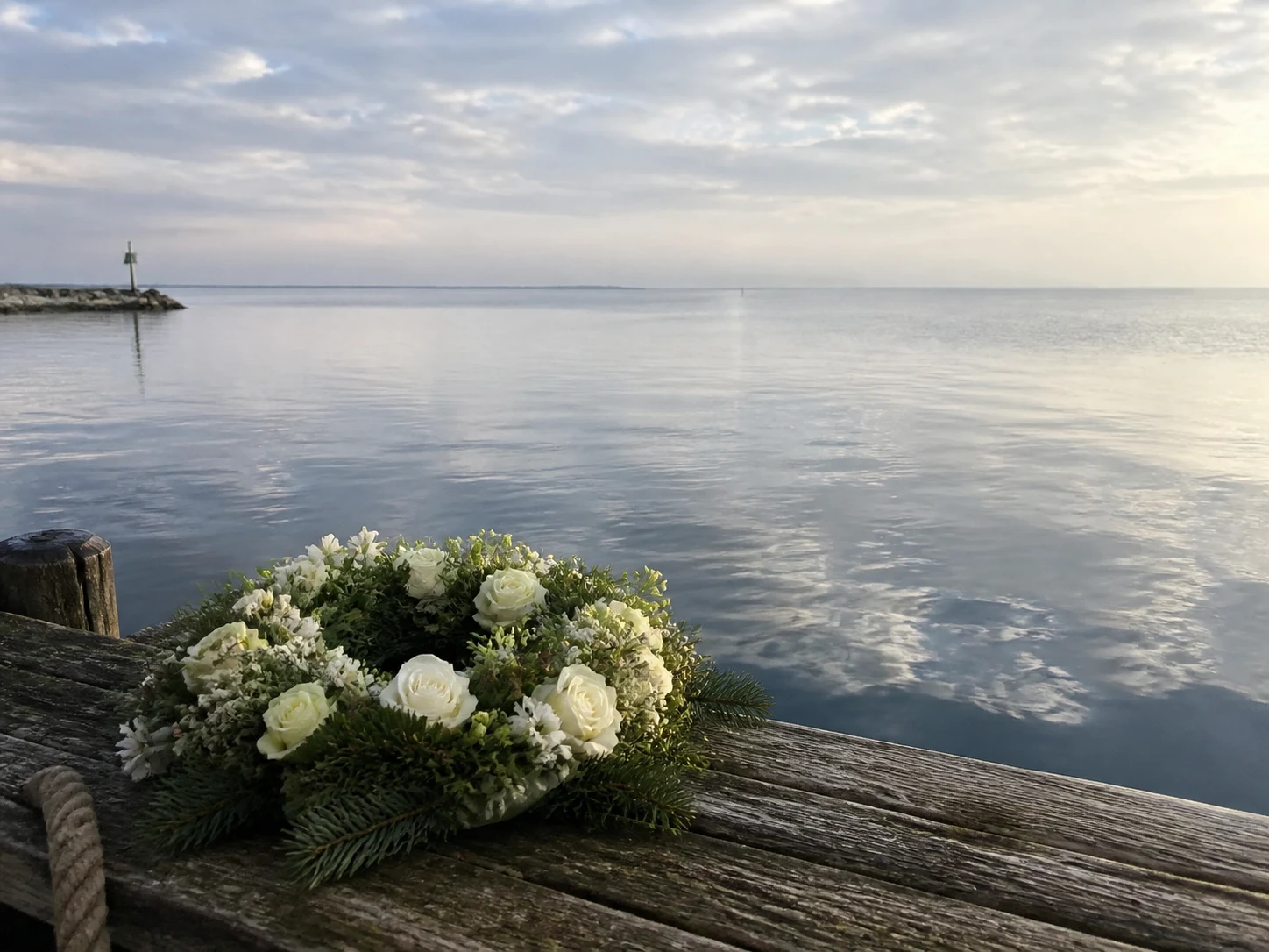 Weißer Trauerkranz auf einem Bootssteg an der ruhigen Nordsee